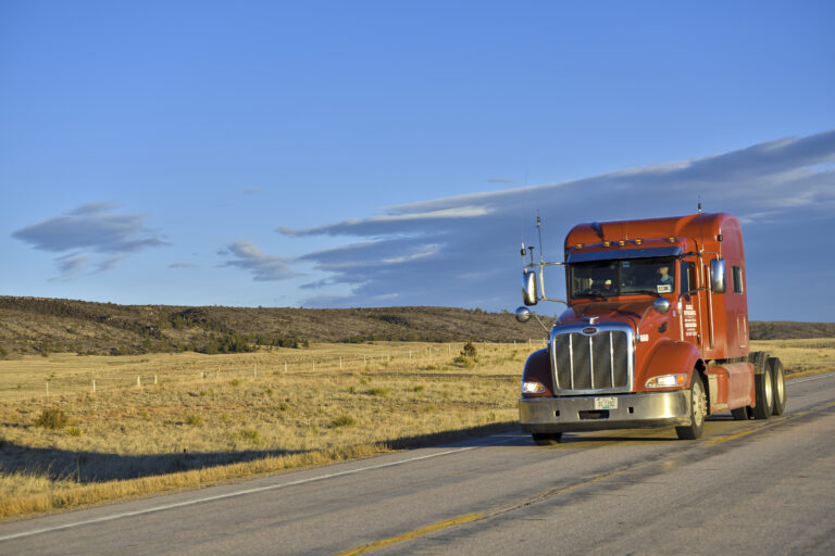 Alt Text: Red Peterbilt truck driving on a highway