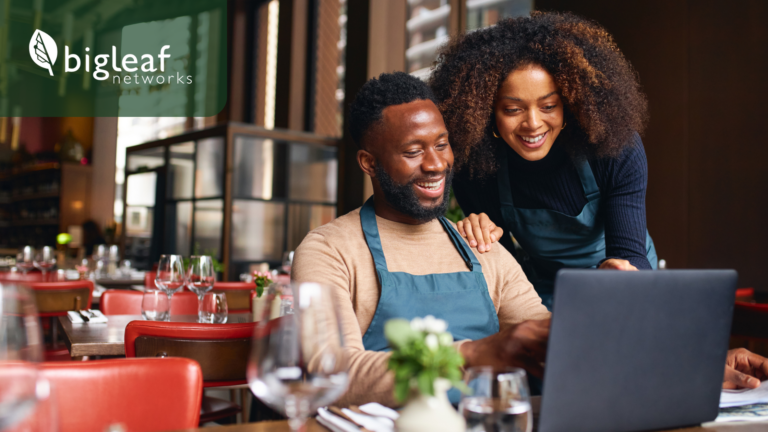 Restaurant owners discussing over a laptop with Bigleaf Networks visible on the screen.